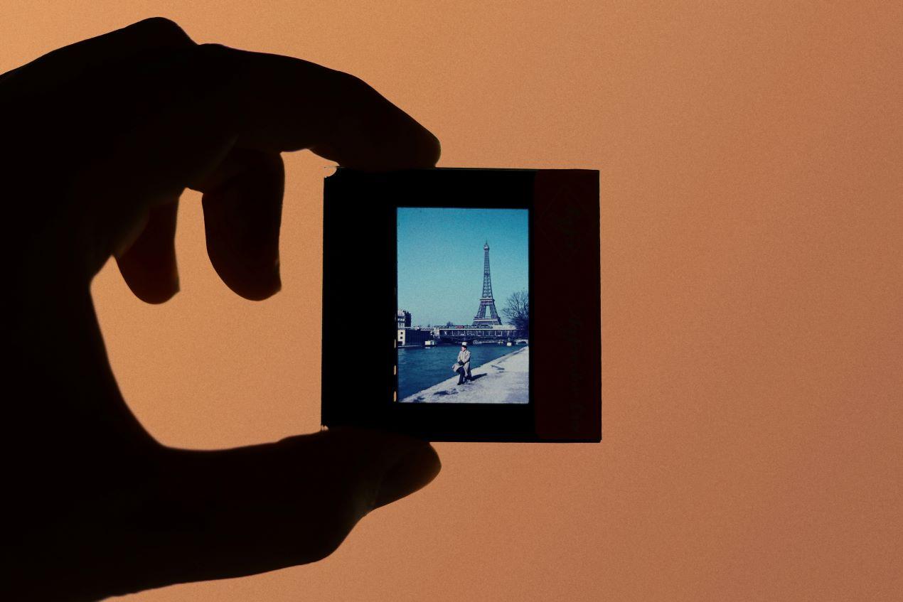 Hand hält ein Dia-Negativ mit Eiffelturm-Motiv – ein Beispiel für hochwertige Ergebnisse beim Negative digitalisieren lassen.